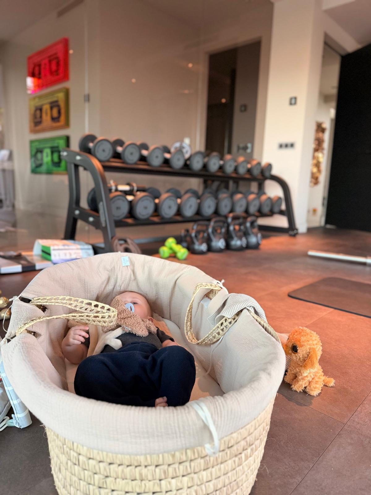 Mama-leven met baby naast de dumbbells